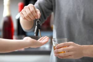 driver handing over car keys while holding a drink